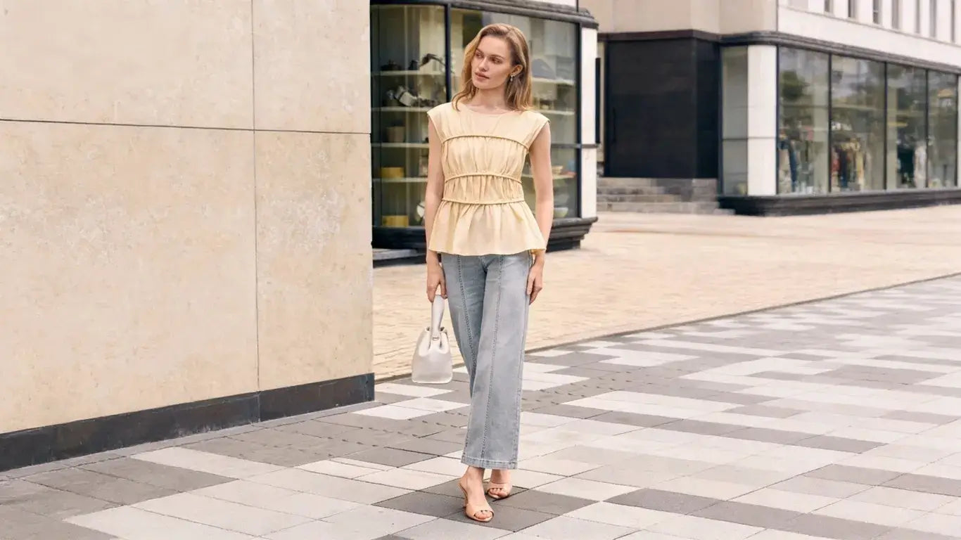 Woman in beige peplum top & light wash jeans, city street with geometric pavement