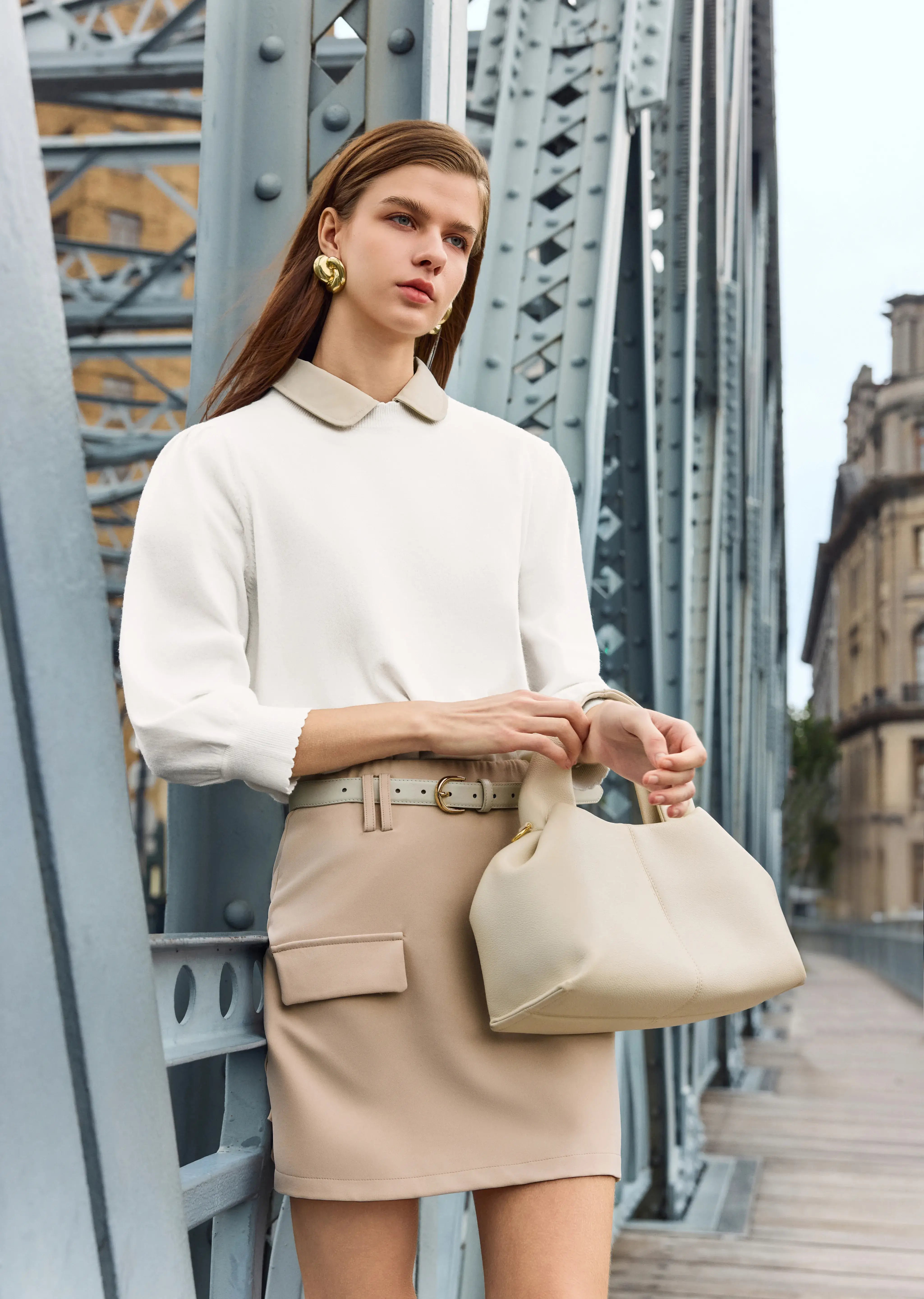 The woman is wearing a Peter Pan collar top paired with a knitted sweater.