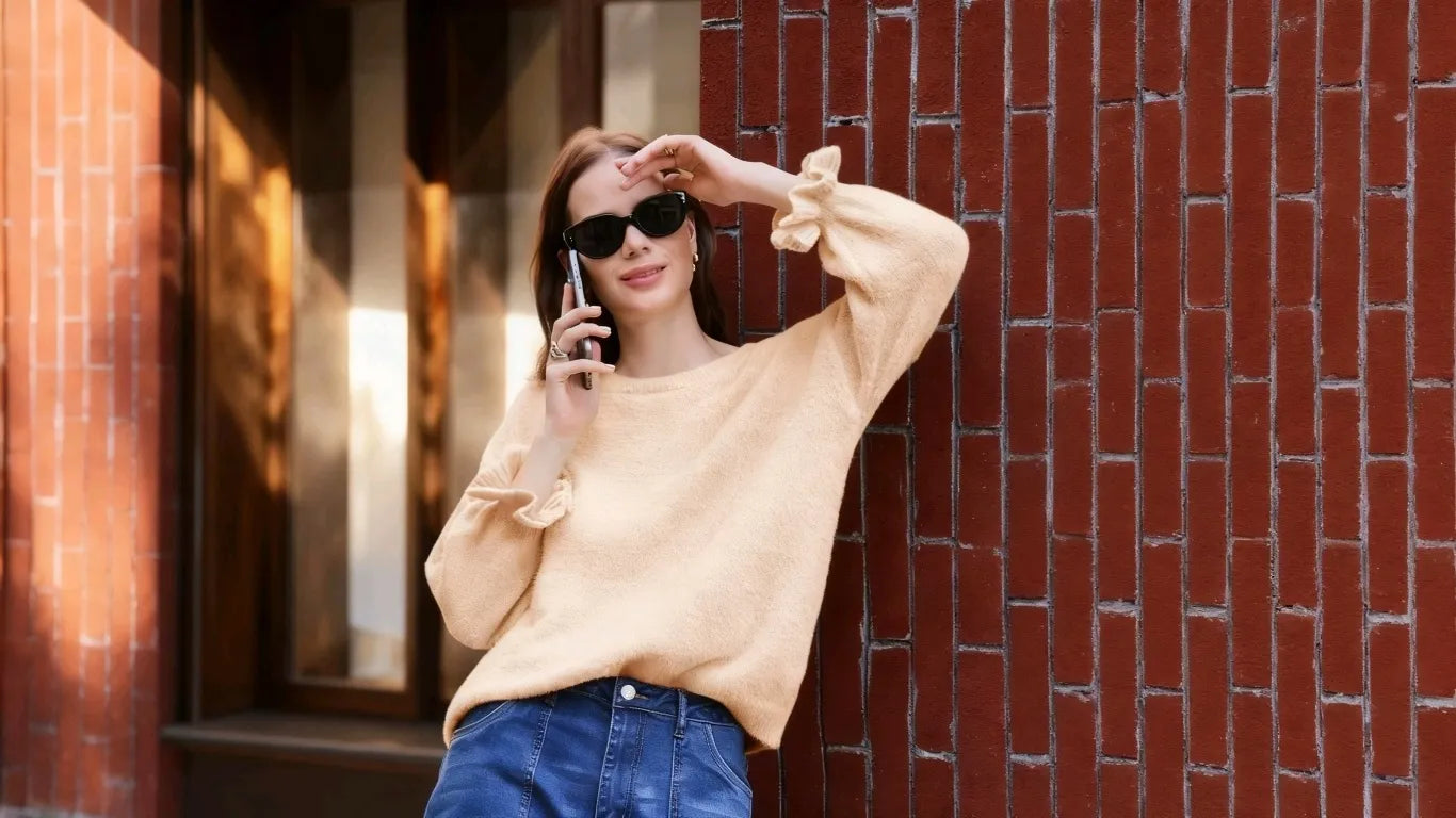 A woman wearing Cicy Bell Women's Apricot Ruffle Sweaters leaned against the wall.