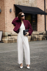 Professional woman wearing a smart casual outfit with a Cicy Bell burgundy cropped pea coat and white high-waisted wide-leg trousers