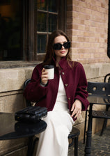 Elegant woman in a chic burgundy winter cropped coat having coffee outside, styling an old money aesthetic look