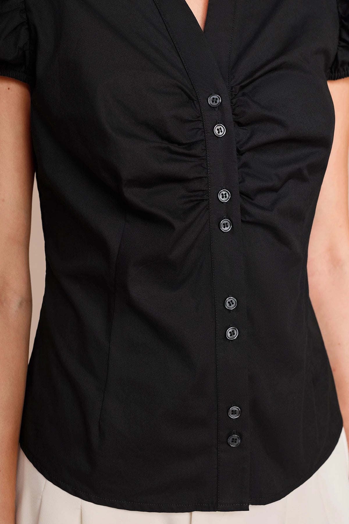 Close-up of flattering ruched detailing and buttons on a women's black slim fit summer blouse