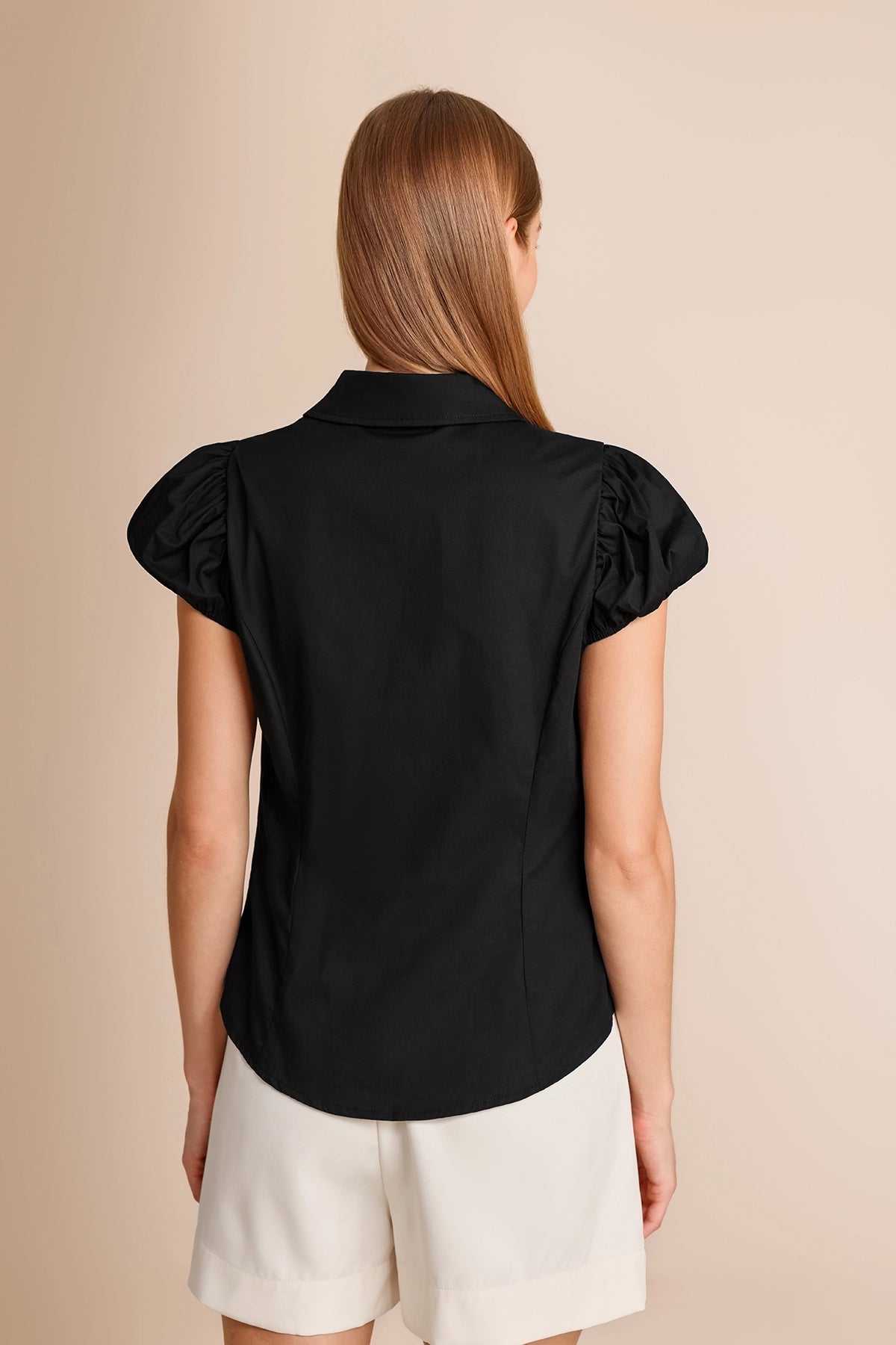 Back view of a women's black puff sleeve top showing the flattering curvy hem design