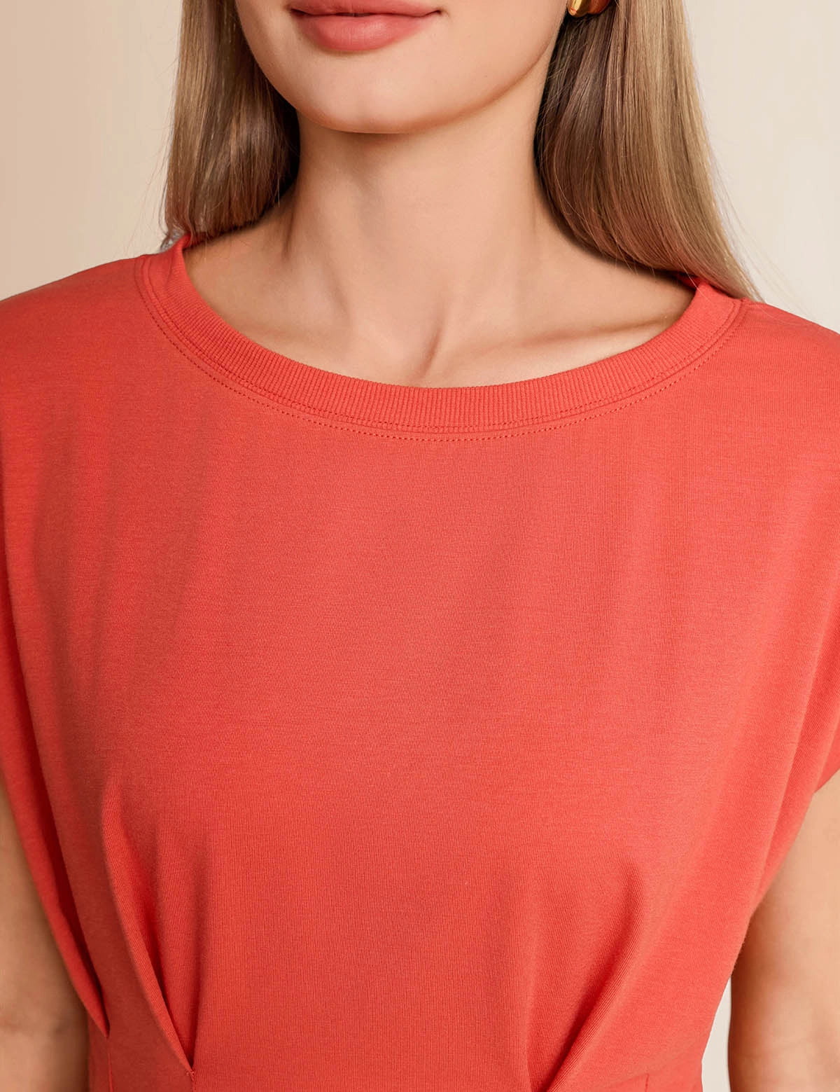 Close-up of the classic crew neck and structural front pleats on a women's brick red summer blouse