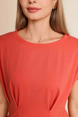 Close-up of the classic crew neck and structural front pleats on a women's brick red summer blouse