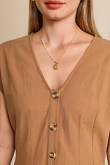 Close-up of tortoise-shell buttons and deep V-neck on a tailored women's warm khaki cotton vest