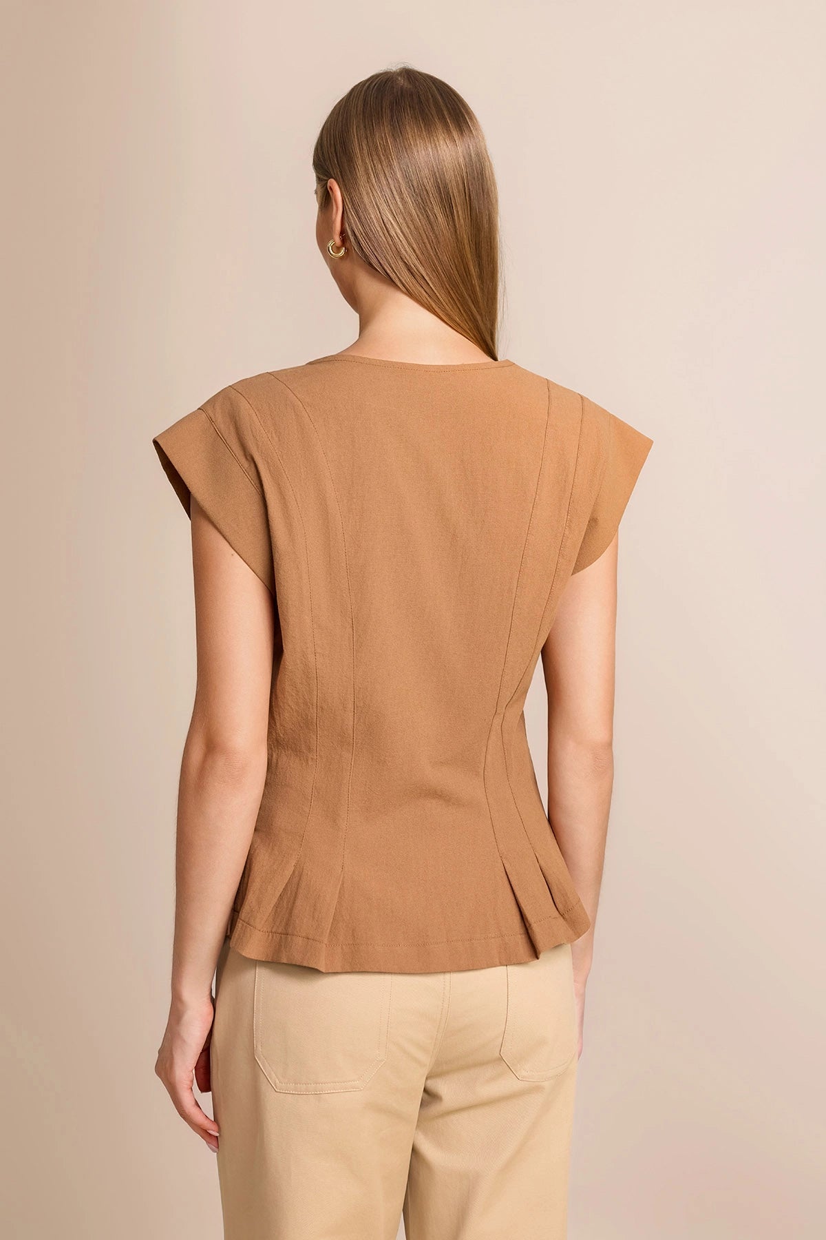 Back view of a women's tailored cotton vest showing the flattering cinched waist and cropped ruffle hem