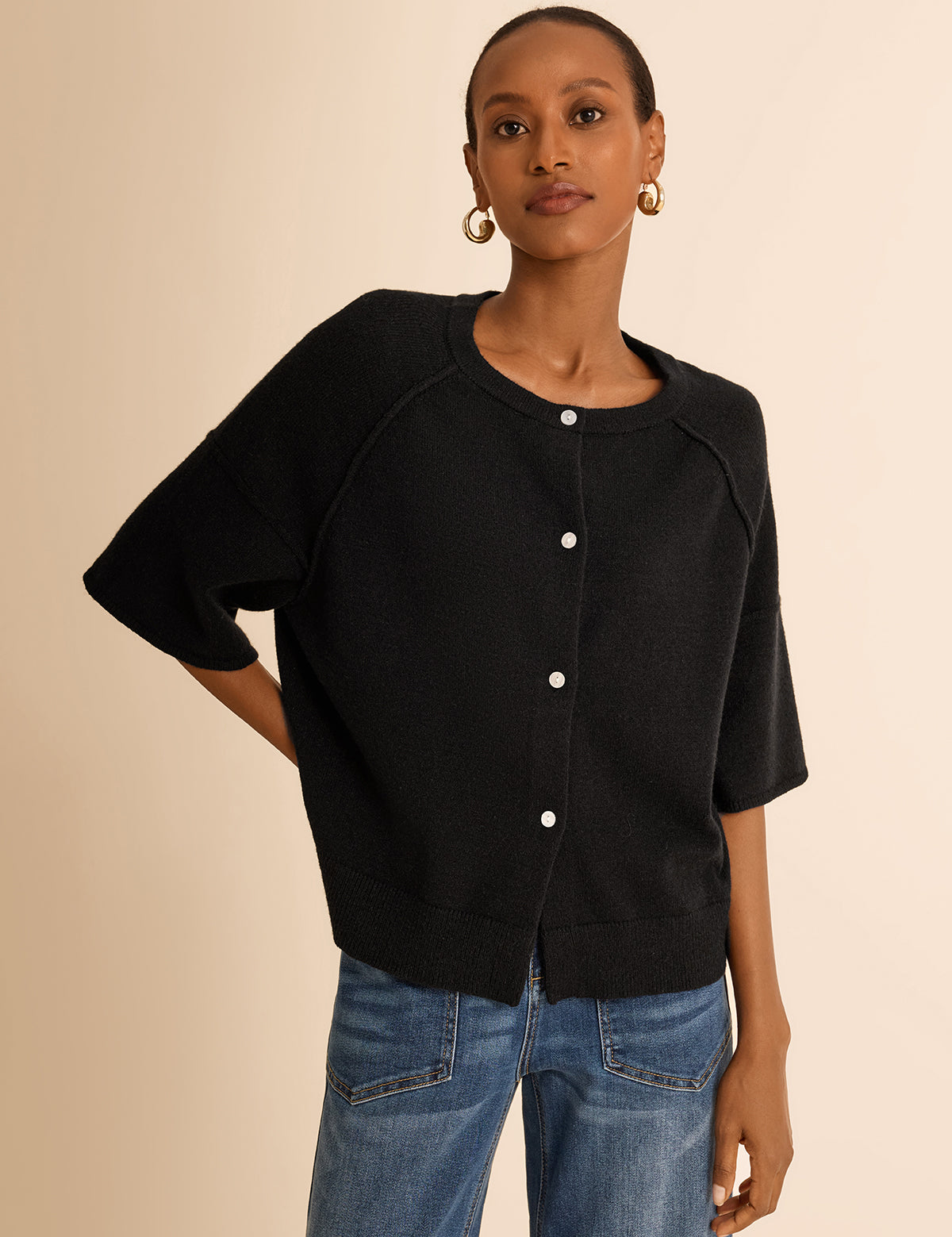 Cicy Bell Women's Button-Down Cardigan featuring trendy half sleeves and chic exposed seam detailing. This lightweight cropped knit sweater offers a relaxed drop shoulder silhouette and a ribbed crew neck for a cozy yet polished spring layer.
