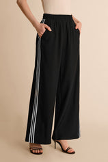 CicyBell Women's High-Waisted Wide-Leg Pants with bold contrasting side stripes. These sporty-chic trousers feature a comfortable elastic waistband and modern side slits for an effortlessly fashionable travel look.
