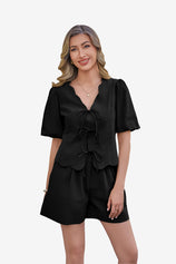 CicyBell Women's Black 2 Piece Set in 100% cotton. A model showcases the tie-front puff sleeve top with a romantic ruffle V-neck and matching high-waisted wide-leg shorts, perfect for a coordinated summer loungewear or beach look.