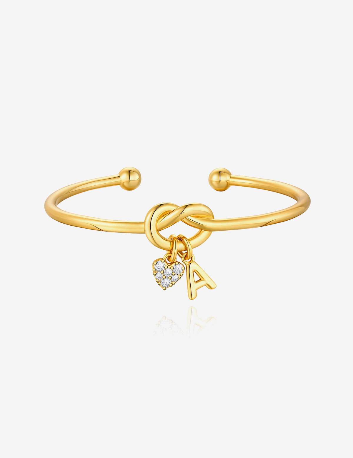 Cicy Bell Women's 18k Gold Plated Initial Bangle featuring a symbolic love knot design and a sparkling CZ heart charm. This personalized open-cuff bracelet offers an adjustable $60\text{mm}$ fit for bridesmaids or best friends.