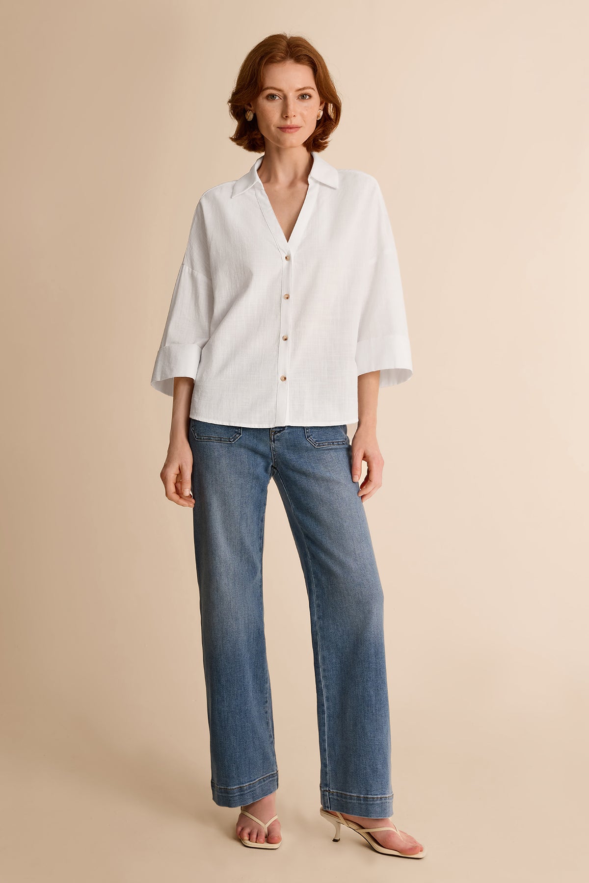 Summer office outfit idea featuring an oversized white cotton blend blouse tucked into straight-leg blue jeans
