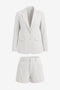 Cicy Bell Women's 2-Piece Blazer and Shorts Set featuring a tailored notch lapel blazer and high-waisted cuffed mini shorts. This polished summer power suit includes a single-button closure and functional pockets in a stretch-infused, wrinkle-resistant blend.